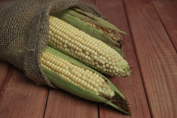 Poster - Fresh Sweet corn in bag on a red   wooden table beautiful background.