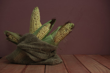 Poster - Fresh Sweet corn in bag on a red   wooden table and beautiful red wall background.
