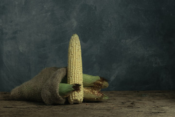 Poster - Fresh Sweet corn in bag on a old oak  wooden table and beautiful grey wall background.