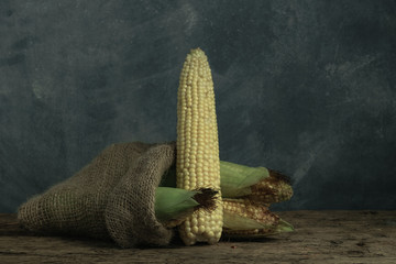 Poster - Fresh Sweet corn in bag on a old oak  wooden table and beautiful grey wall background.