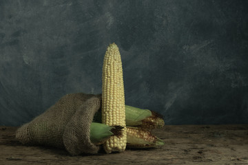 Poster - Fresh Sweet corn in bag on a old oak  wooden table and beautiful grey wall background.