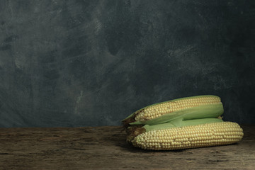 Poster - Fresh Sweet corn on a old oak  wooden table and beautiful grey wall background.