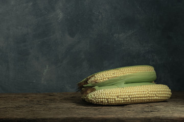 Poster - Fresh Sweet corn on a old oak  wooden table and beautiful grey wall background.
