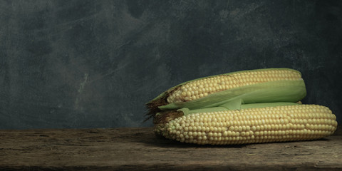 Poster - Fresh Sweet corn on a old oak  wooden table and beautiful grey wall background.