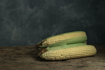Poster - Fresh Sweet corn on a old oak  wooden table and beautiful grey wall background.