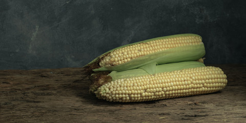 Poster - Fresh Sweet corn on a old oak  wooden table and beautiful grey wall background.
