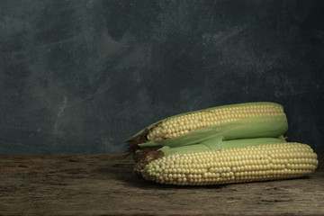 Poster - Fresh Sweet corn on a old oak  wooden table and beautiful grey wall background.