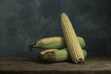 Poster - Fresh Sweet corn on a old oak  wooden table and beautiful grey wall background.