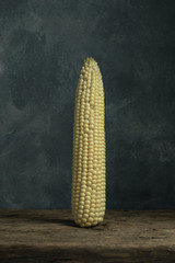 Poster - Fresh Sweet corn on a old oak  wooden table and beautiful grey wall background.