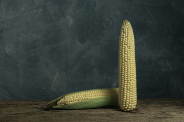 Poster - Two Fresh Sweet corn on a old oak  wooden table and beautiful grey wall background.