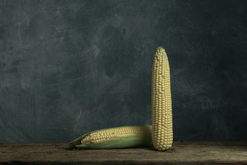 Poster - Two Fresh Sweet corn on a old oak  wooden table and beautiful grey wall background.