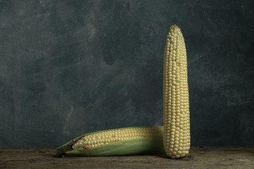 Poster - Two Fresh Sweet corn on a old oak  wooden table and beautiful grey wall background.