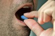 Hand of man holding blue pill. Closeup of a man taking blue medicine pill. Mouth view, illness. Medicine concept of viagra, medication for stomach, erection, sleeping, digestive or drugs