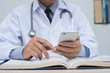 Doctor using smartphone and reading book