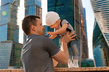 Father and one year old son against the sky and skyscrapers. Travel with children, the development of emotional intelligence. Early development.