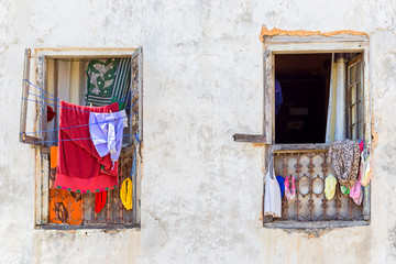 two windows with clothes hanging on the window frame and washline