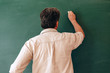 © speed300 - Teacher write on the blackboard and explain a lesson. Back view- Image