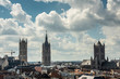 Gent, Flanders, Belgium -  June 21, 2019: Shot from castle tower, view over city roofs shows three most important and historic towers of Belfry, Cathedral and Sint Niklaas church under heavy cloudscap