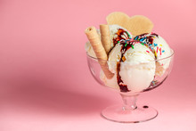 Scoops Of Sundae Ice Cream In Glass Bowl With Chocolate Sauce, Strewed Sprinkles And Cookies On Pink Background