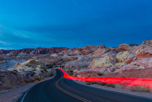 USA, Nevada, Valley Of Fire State Park, Sandstone And Limestone Rocks, Light Trails Of A Car On Scenic Road At Twilight