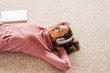 © Westend61 - Woman lying on carpet wearing headphones