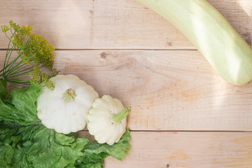 Homemade vegetables. Squash Squash white and lettuce on a wooden background. Green harvest on wooden background. Courgettes on a wooden background. Healthy food. Organic Products