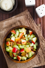 Wall Mural - Fresh Waldorf salad made of celery, apple, walnuts, sultanas and raisins in wooden bowl with mayonnaise on the side, photographed overhead