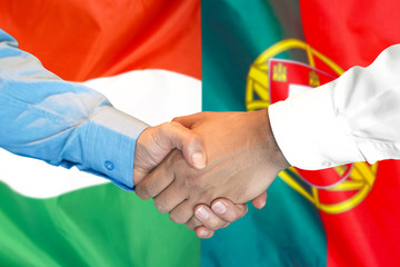 Business handshake on the background of two flags. Men handshake on the background of the Hungary and Portugal flag. Support concept