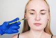 © Siniehina - A cosmetologist carries out a procedure - an injection into the face of a young woman. Beauty injections, mesotherapy, hyaluronic acid injections, biorevitalization, cheek correction, fillers