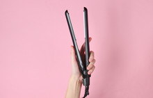 Hair Care. Female Hand Holding Hair Straightener On Pink Background. Top View