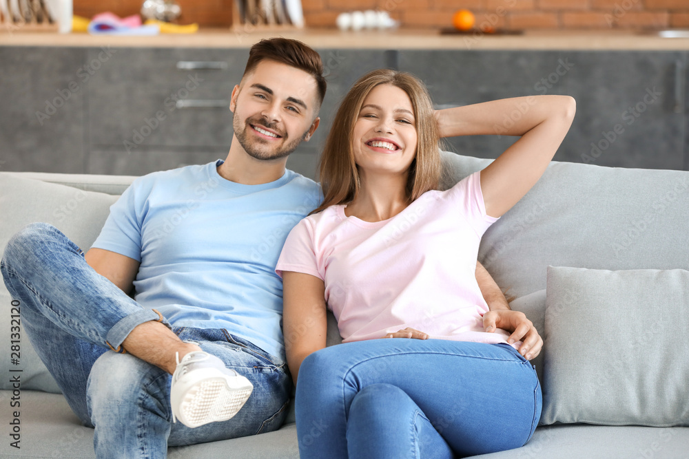 Happy young couple resting together on sofa at home