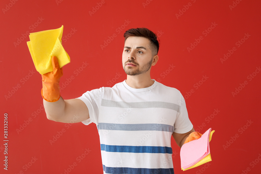 Sad young man with cleaning rags on color background