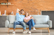 © Pixel-Shot - Happy young couple resting together on sofa at home