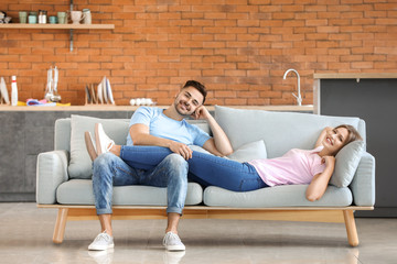 Wall Mural - Happy young couple resting together on sofa at home