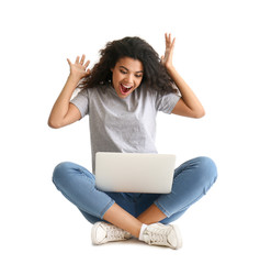 Portrait of excited African-American woman with laptop on light background