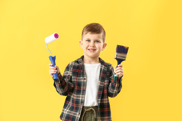 Wall Mural - Cute little boy with paint roller and brush on color background