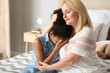 Woman calming her crying African-American daughter at home