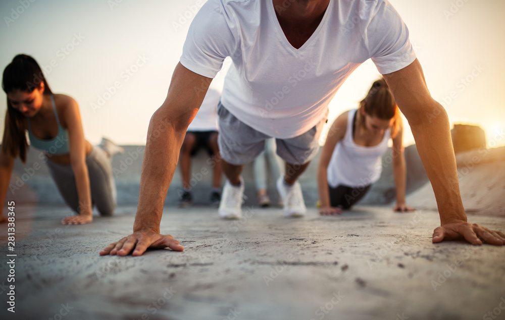 Group of athletic young people, friends in sportswear doing exercises. Sport outdoors