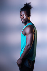 Wall Mural - handsome, muscular african american sportsman posing at camera on grey background with lighting