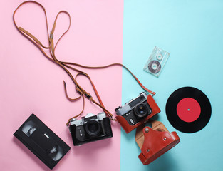 Wall Mural - Retro top view still life. Vinyl record, vintage film camera, video and audio cassette on blue pink pastel background. Flat lay. Top view