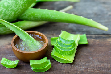 Fresh aloe vera stem slices and gel on wooden table, skin therapy concept