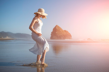 Wall Mural - A girl in a hat at sunset near the ocean splashes