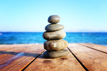 Stones Pyramid On Over Beach Wooden Deck Symbolizing Harmony, Zen And Balance