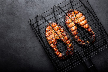 Wall Mural - Grilled salmon on iron grill grate on a dark background top view. BBQ seafood. spece for a text