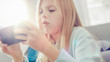 © Gorodenkoff - Close-Up Portrait of a Smart Girl Sitting on Carpet at Home Playing in Video Game on Her Smartphone, Holds and Uses Mobile Phone in Horizontal Landscape Mode. She Has Fun Playing Games in Living Room.