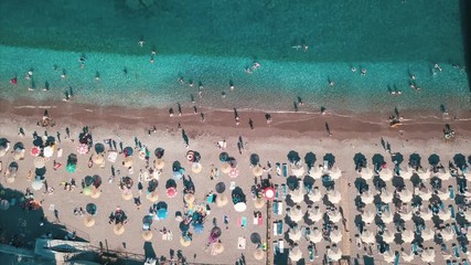 Wall Mural - Aerial top view of beach with sunshade and people swimming at beautiful blue color sea