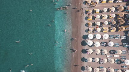 Wall Mural - Aerial top view of beach with sunshade and people swimming at beautiful blue color sea