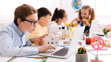 Poster - Schoolboy programming diy robot with laptop at stem lesson