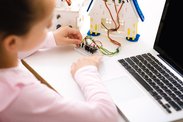 Schoolgirl programming robot with laptop computer at lesson