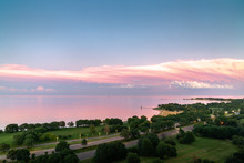 Gorgeous Aerial Sunset View Of Calm Water Of Lake Michigan With Pink Feathery Clouds Layered Over White Fluffy Clouds And Panoramic View Of Montrose And Foster Beach Along Lake Shore Drive In Chicago.